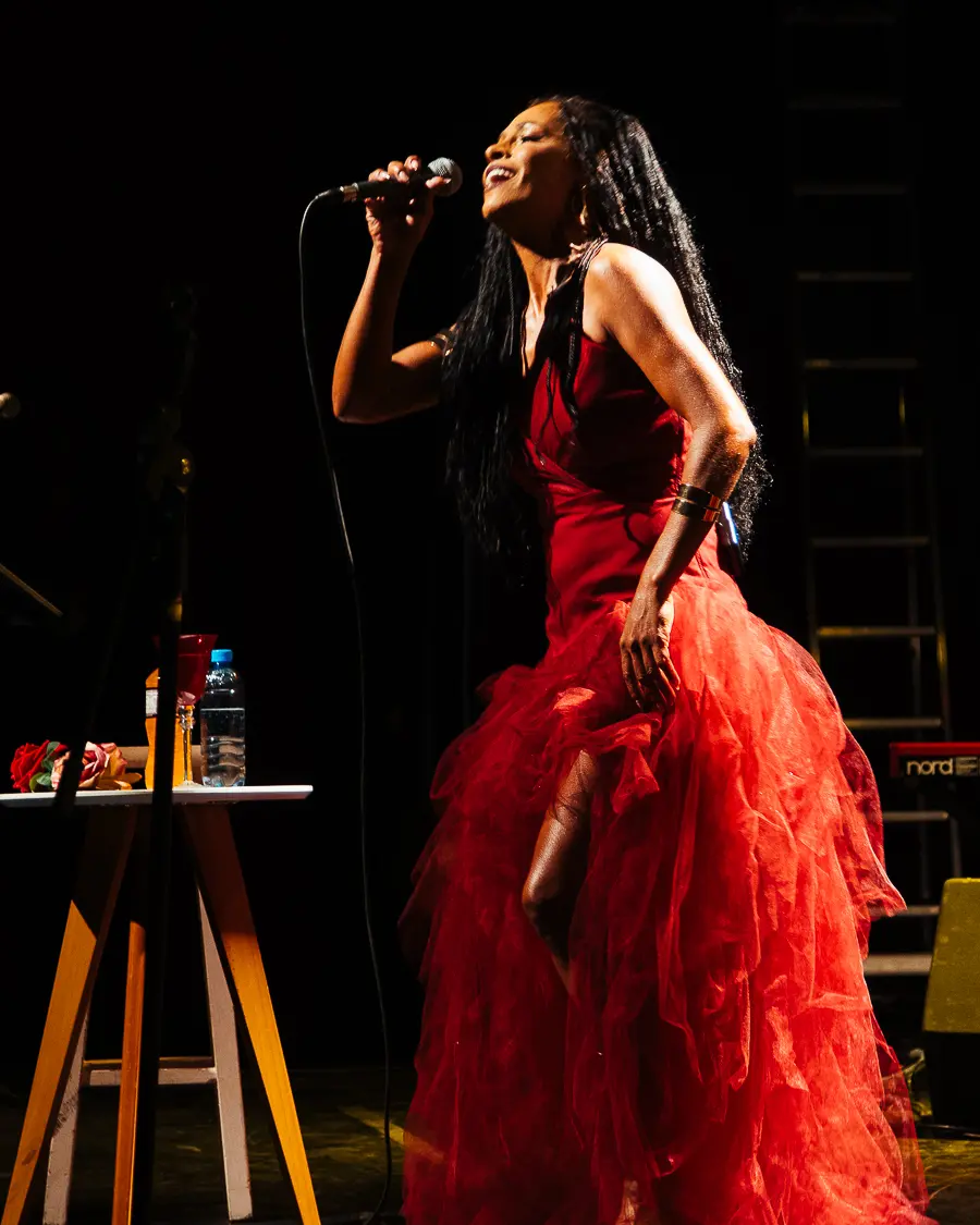 Gizelly di Sousa cantando de corpo inteiro com figurino vermelho