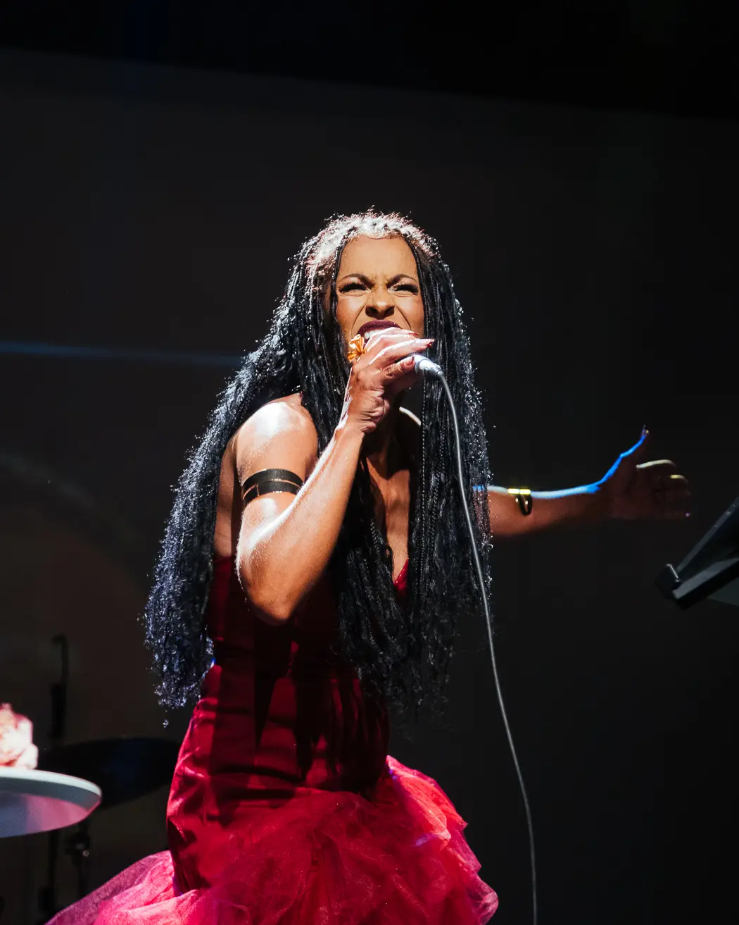 Gizelly di Sousa cantando com intensidade sob as luzes do palco